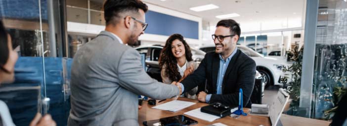 Dealership_sales_rep_smiling_with_customers_shaking_hands.jpg
