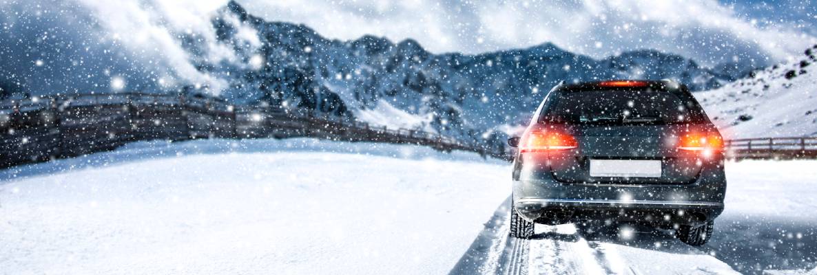 An SUV drives through a snowy landscape towards a forest