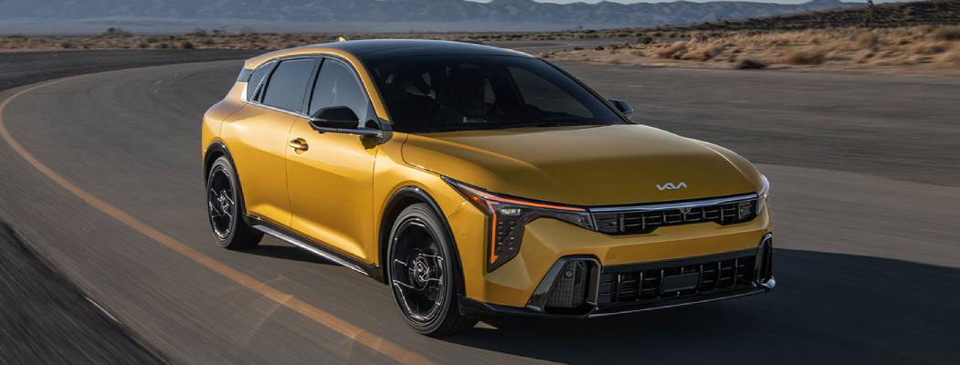 A yellow 2026 Kia K4 Hatchback drives by the camera at an angle