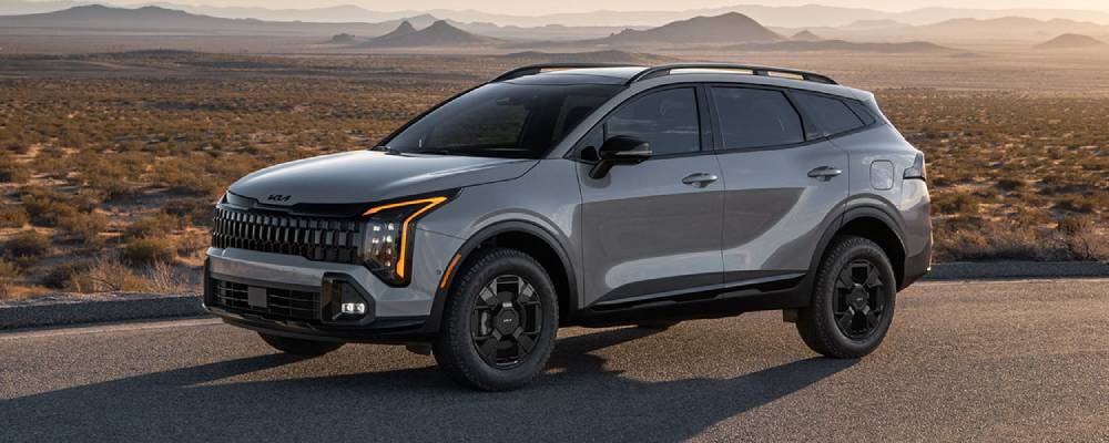 A silver 2026 Kia Sportage parked on off-road terrain. 2026 Kia Sportage vs 2025 Kia Sorento at Lally Kia in Chatham, ON