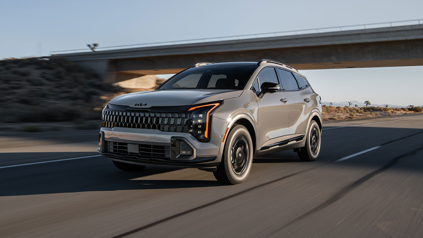 A 2026 Kia Sportage drives on a highway. 2026 Kia Sportage vs 2025 Kia Sorento at Lally Kia in Chatham, ON